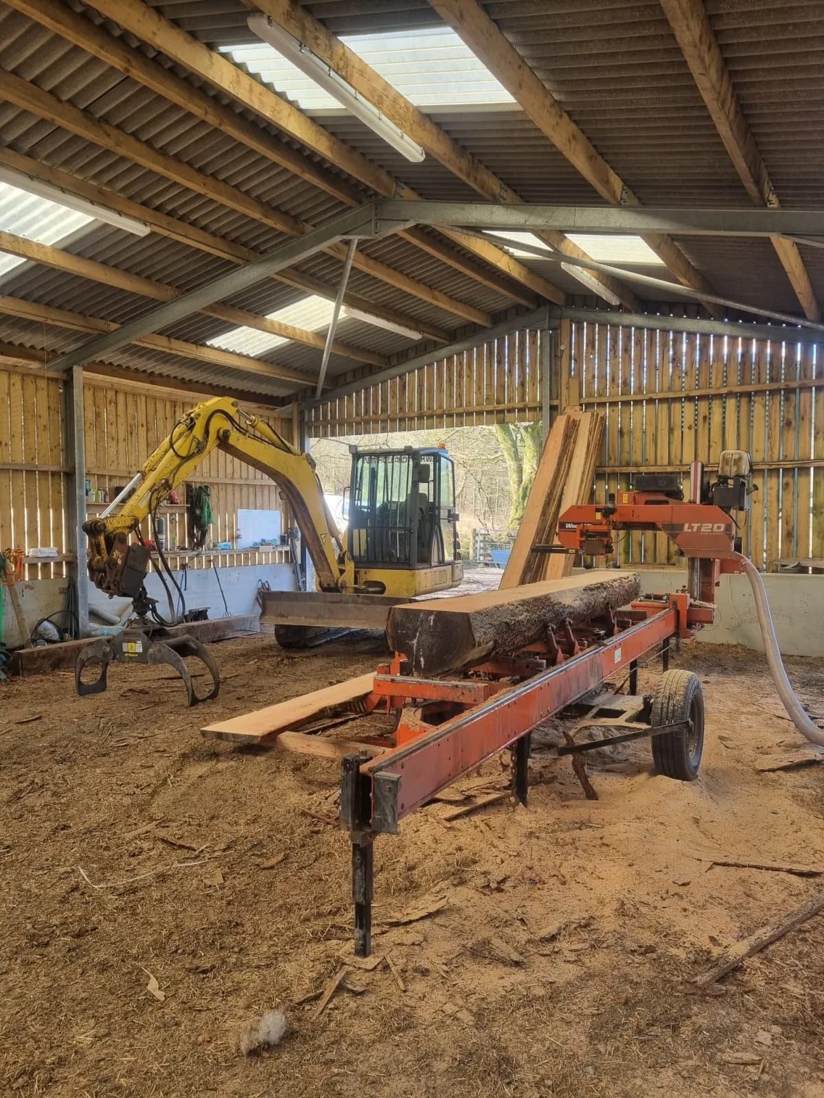 Mobile sawmill set up in the yard shed, cutting a log to length